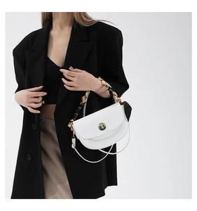 Detail of white saddle bag with golden lock and chain handle woven with silk scarf