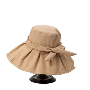 Women's beige wide brim sun hat with ribbon bow and textured fabric on wooden stand