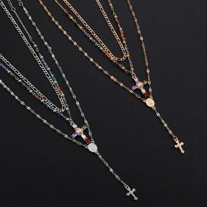 Close-up of layered cross and Madonna pendants with colorful beads on gold and silver chains