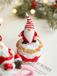 Detailed view of resin Christmas gnome figurine on cake base with festive warm lighting