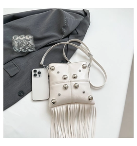 Flat lay of a white rivet crossbody bag with long fringes and a matching shoulder strap