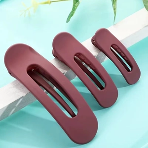 Tres pinzas para el cabello en color granate mate en diferentes tamaños en un soporte