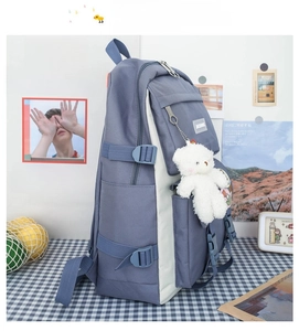 Detailed side view of blue and white campus backpack with teddy bear plush charm