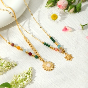 Gold layered sun pendant necklace with colorful natural stone beads and floral backdrop