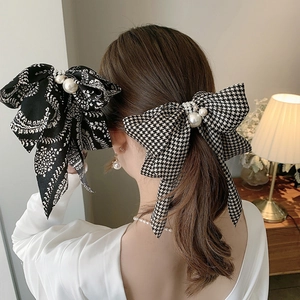 Detail of elegant houndstooth and vintage paisley bow clips with pearl embellishments