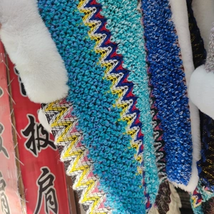 Close-up of wavy blue knit texture and soft white faux fur trim on ethnic style shawl