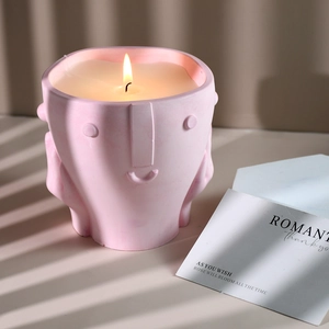 Artistic pink face shaped candle with hand-on-chin design and warm lighting detail