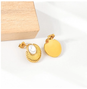 Close-up of vintage gold plated oval pearl stud earrings with a textured shell pattern