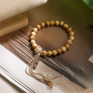 Macro shot of sandalwood beads with cat charm and colorful tassel on magazine