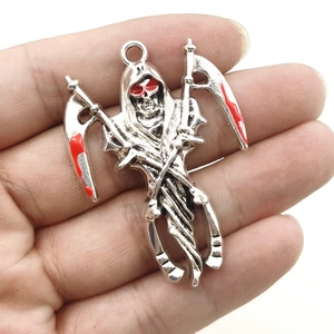 Detail of silver skull reaper pendant with red sickle accent held between fingers