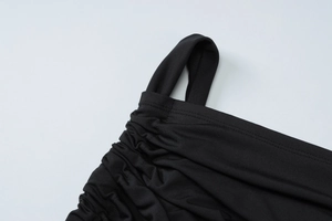 Détail macro du tissu élastique plissé noir et de la connexion des bretelles sur la robe