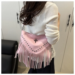 Pink leather shoulder bag with tassels and metallic cross pendant shown in lifestyle setting