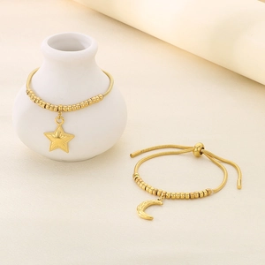 Detail view of gold beaded slider bracelets with star and moon charms in stainless steel