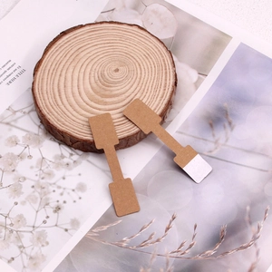Close-up of brown kraft paper jewelry price tags on a natural wood slice background