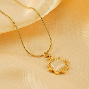 Gold stainless steel snake chain necklace with a square cream white stone pendant on satin