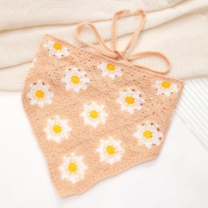 Close-up of orange crochet triangle kerchief featuring white and yellow daisy patterns