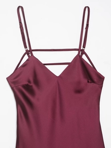 Detail of burgundy satin slip dress showing V-neck and multi-strap design on white background