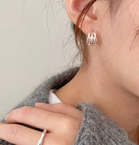 Detail of minimalist silver woven nesting earrings worn with a matching wavy ring