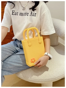 Detail der gelben EVA-Strandtasche mit süßem orangefarbenem Blumenanhänger