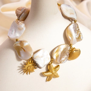 Detail of 18k gold plated sun and starfish charms with iridescent seashell beads