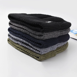 Cinque cappelli invernali da uomo in maglia impilati per colore con etichetta a fiocco