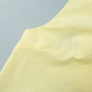Close-up of light yellow fabric dress showing professional stitching and cotton texture