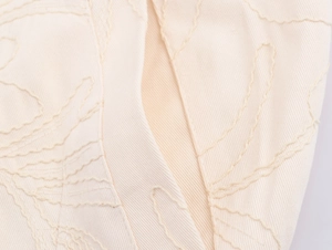 Macro shot of cream embroidery and twill fabric texture on a women casual jacket