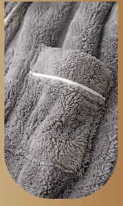 Close-up of thick grey plush bathrobe fabric featuring a pocket with white piping trim