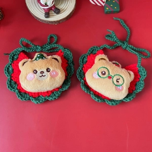 Detail of hand-knitted Christmas pet bib with plush bear on red festive background