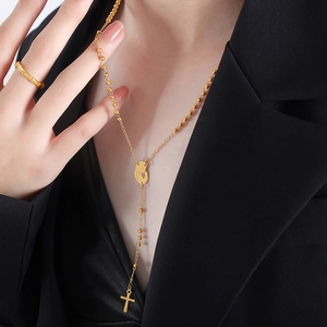 Golden rosary cross necklace with virgin Mary medal and matching ring on black suit