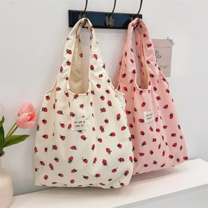 Détail du velours côtelé des sacs cabas à motif fraises suspendus sur un support bois