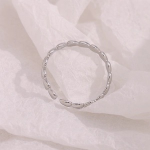 Macro shot of silver minimalist open ring with heart detail on a white textured backdrop