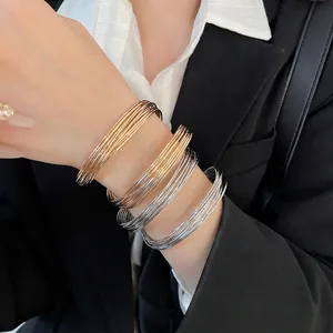 Minimalist twisted gold and silver multi-layered metal bangles worn on a wrist