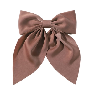 Close-up of a large brown silk satin hair bow clip on a white background with a soft texture
