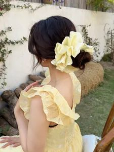 Close-up of a large yellow lace scrunchie with intricate embroidery details on a ponytail