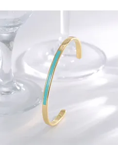 Detail of a minimalist gold open cuff bracelet featuring a turquoise enamel inlay inlay