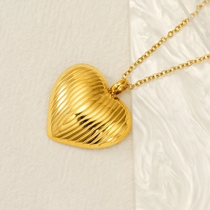 Detailed view of golden heart pendant necklace with textured surface on marble background