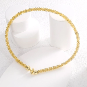 Minimalist gold woven mesh circle choker necklace displayed on a white stone tray