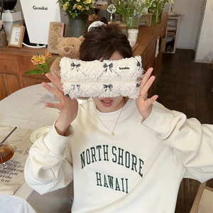 Plush makeup bag with black bow patterns shown in a lifestyle indoor setting
