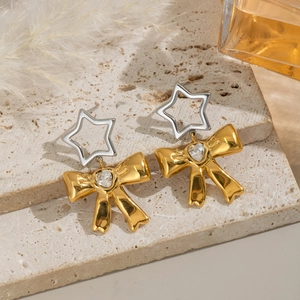 Dettaglio di orecchini a fiocco in oro 18K con stelle argentate e gemme a forma di cuore
