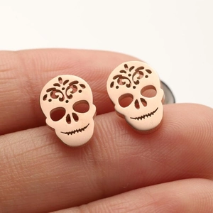 Macro shot of rose gold skeleton stud earrings with intricate cutout floral patterns