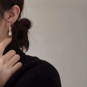 Elegant 925 sterling silver earrings with baroque pearls worn by a model on a grey background