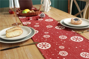 Close-up of a festive red table runner with white snowflake patterns on a wooden table