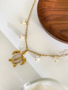 Close-up of titanium steel turtle pendant and freshwater pearls on gold chain necklace