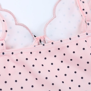 Detailed view of pink polka dot dress showing wavy neckline and shoulder strap stitching