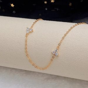 Close-up of gold chain choker with clover pendants and zircon inlays on display