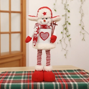 Détail d'un bonhomme de neige en peluche avec pull à cœur et bâtons de ski rouges