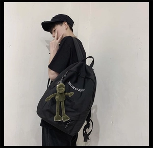 Vue latérale d'un sac à dos noir en toile avec pendentif grenouille sur mannequin