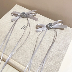 Detail of grey ribbon bow hair clips with rose center on a minimalist book background