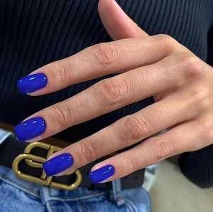 Close-up of electric blue square press-on nails shown on hand with high gloss finish